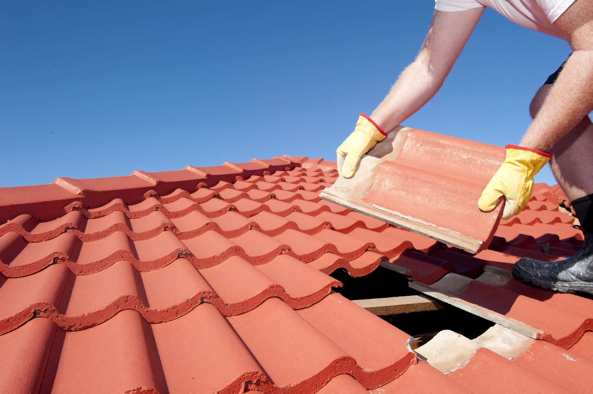 Clay shingles being put in place on a sloped roof.